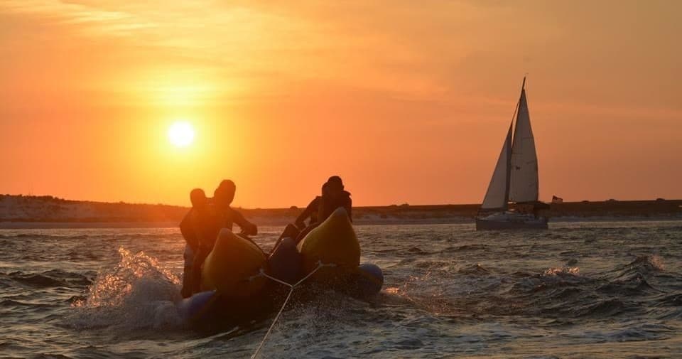 Sunset silhouette of people boating with sailboat offshore