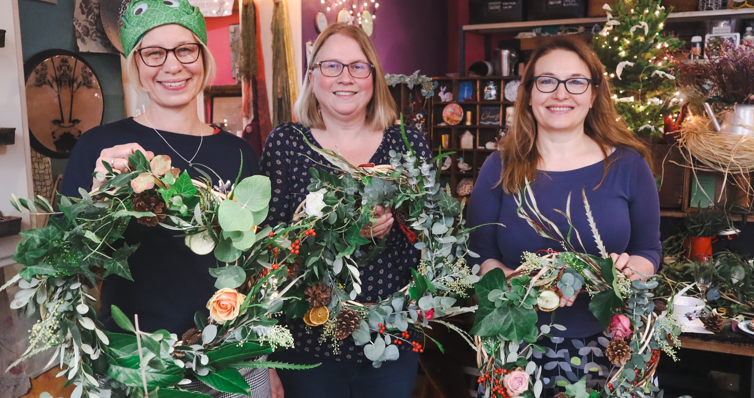 Workshop participants holding handmade wreaths at studio