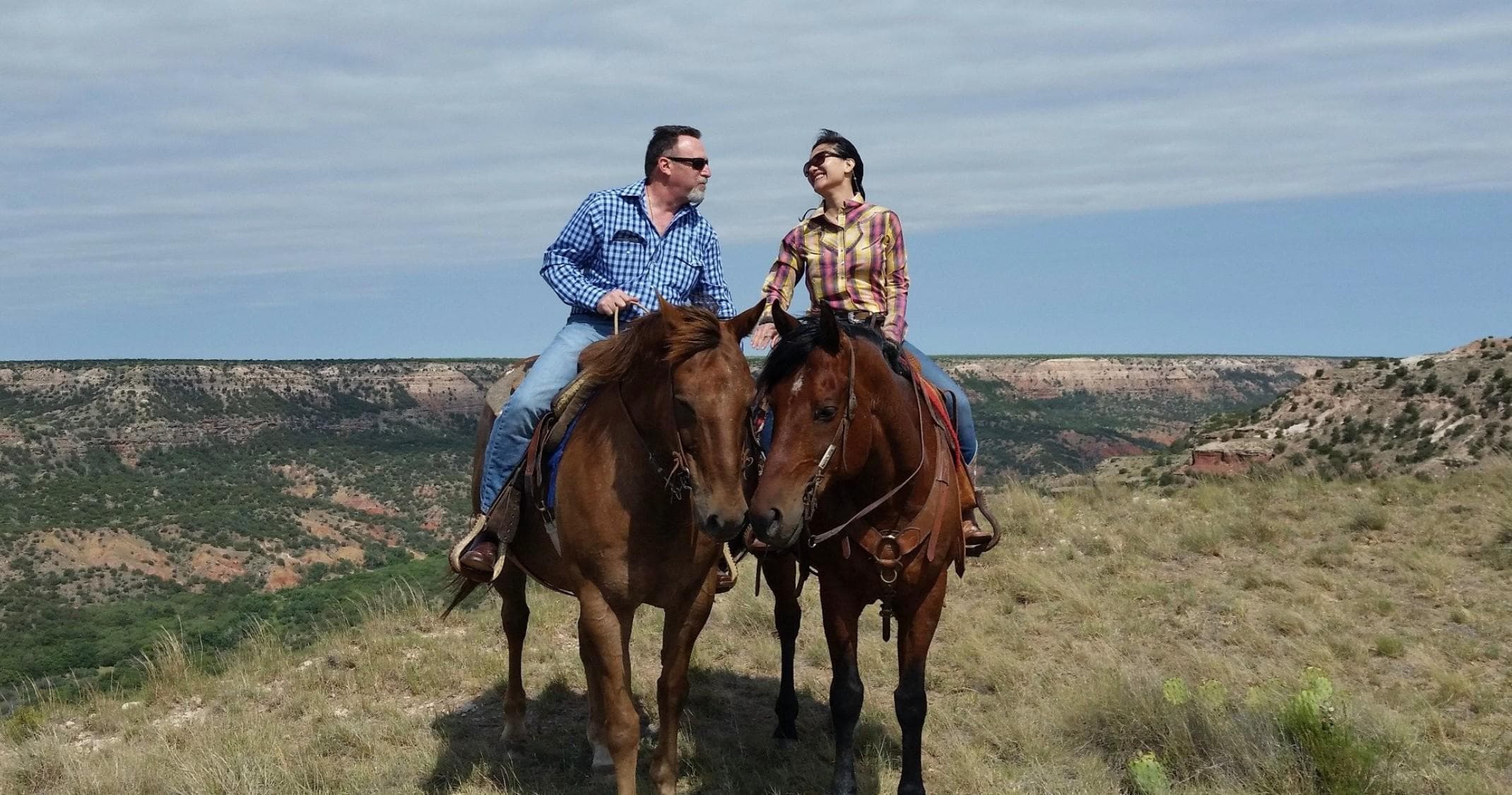 Couple horseback riding along panoramic canyon ridge view