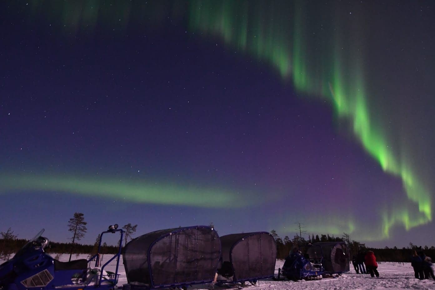 Northern Lights over snowy Arctic camp under vivid sky