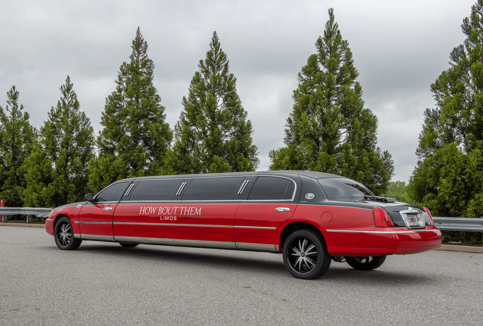 Red stretch limousine parked by trees for group event transportation