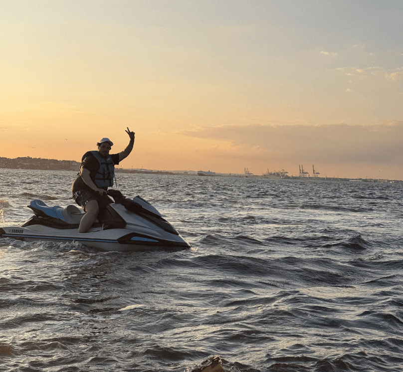 Sunset jet ski silhouette on open water with distant skyline