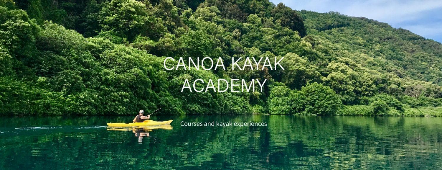 Solo kayaker paddling on emerald lake with forested mountains