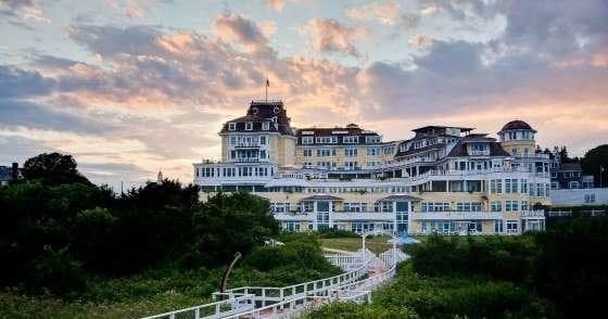 Oceanfront resort mansion on coastal bluff at sunset, scenic view