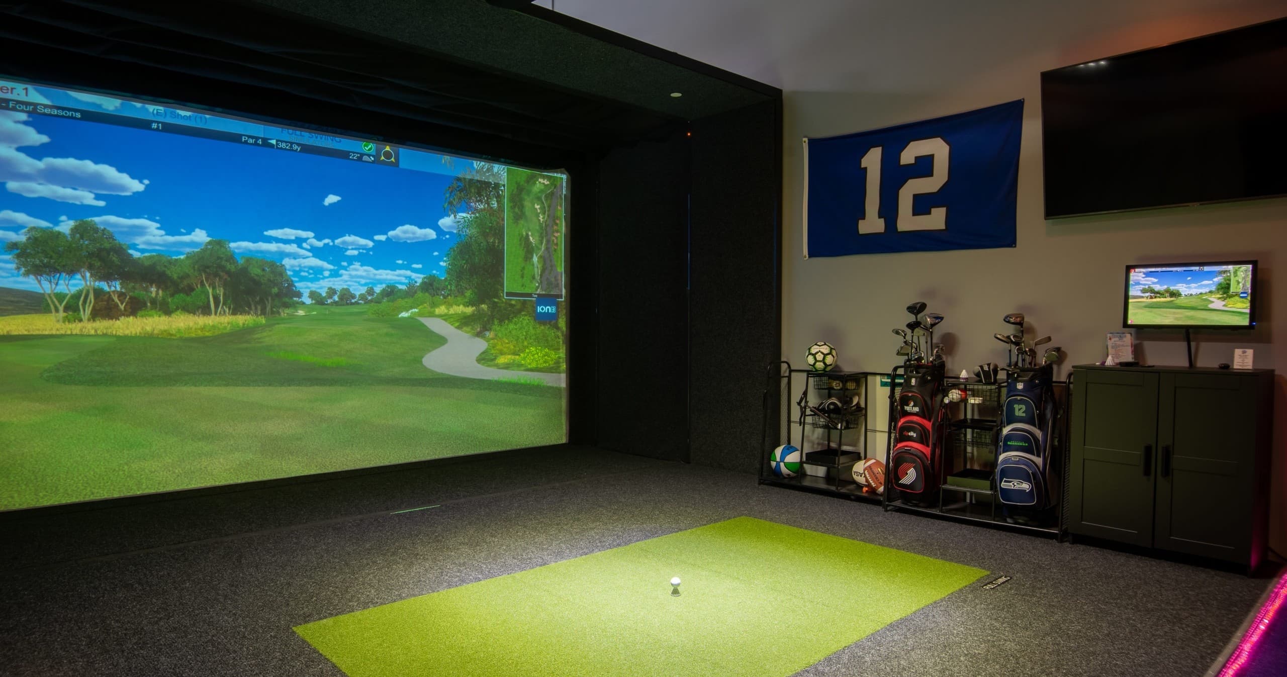 Indoor golf simulator bay with screen and putting green