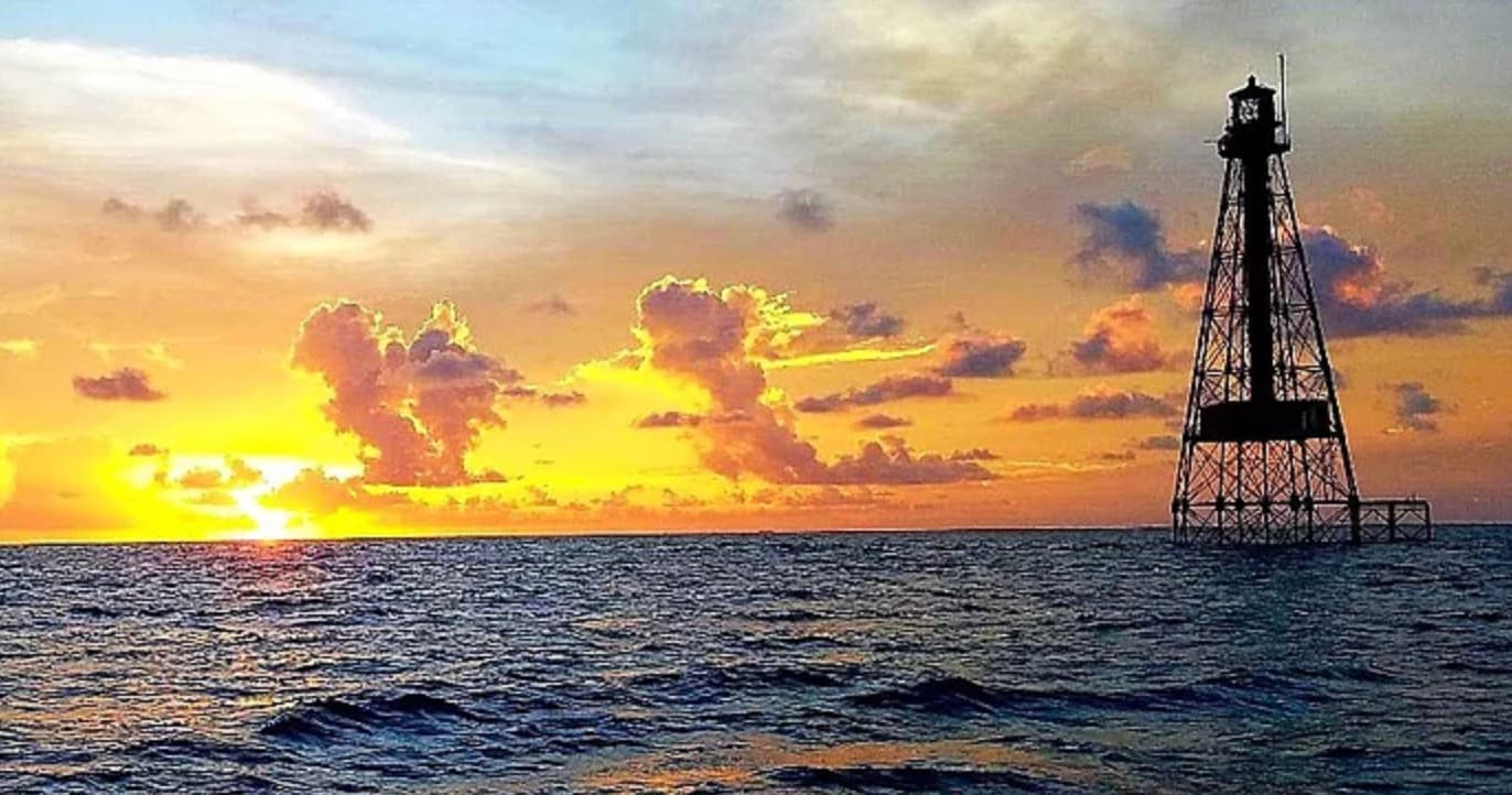 Offshore lighthouse tower at sunset over open ocean, scenic view