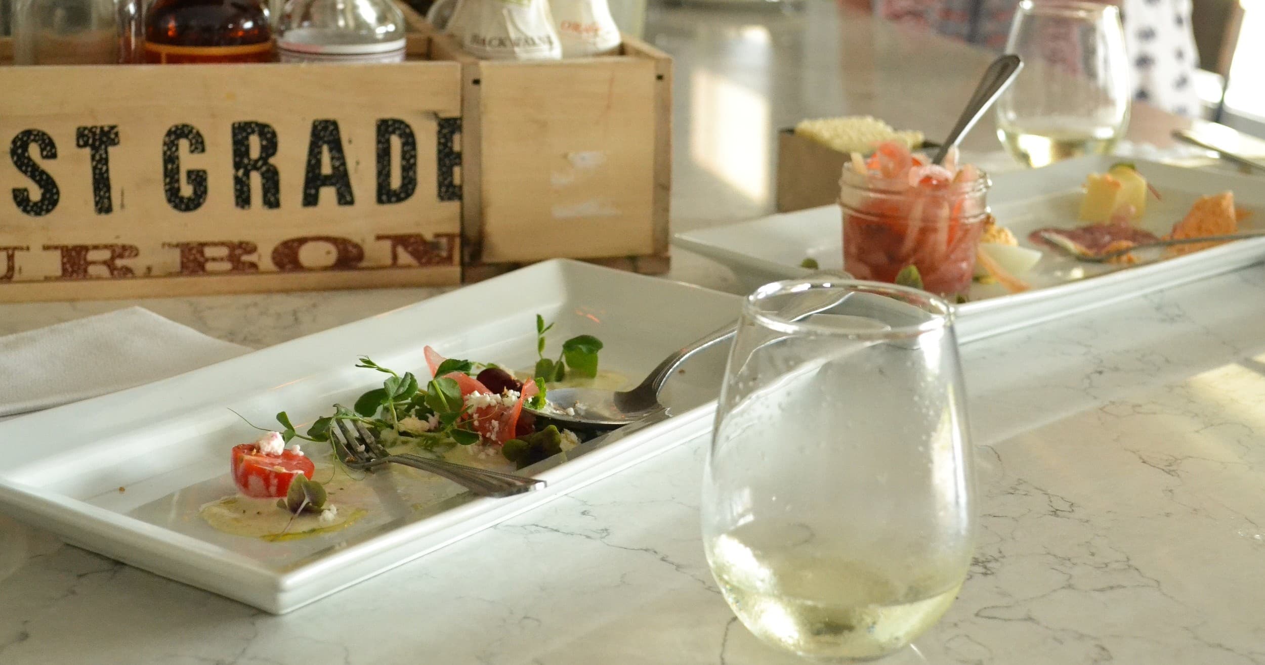 Gourmet plated appetizers and wine glass on indoor tasting counter