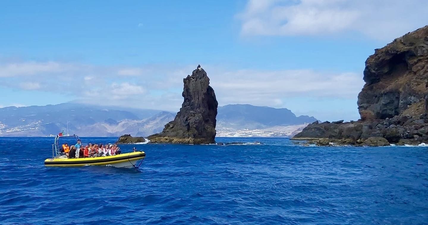 RIB sightseeing boat near dramatic sea stack off Madeira coast
