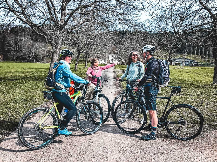 Family cyclists resting on trail in scenic park during spring ride