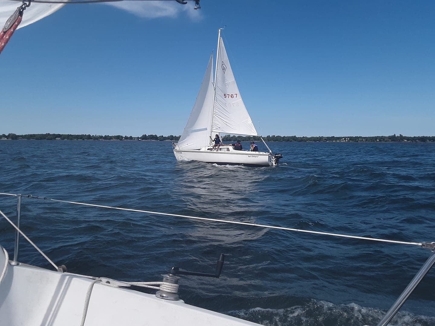 Small sailboat cruising on calm coastal waters under clear sky