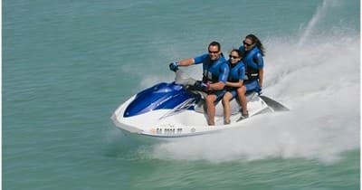 Two riders on jet ski speeding across turquoise lake water