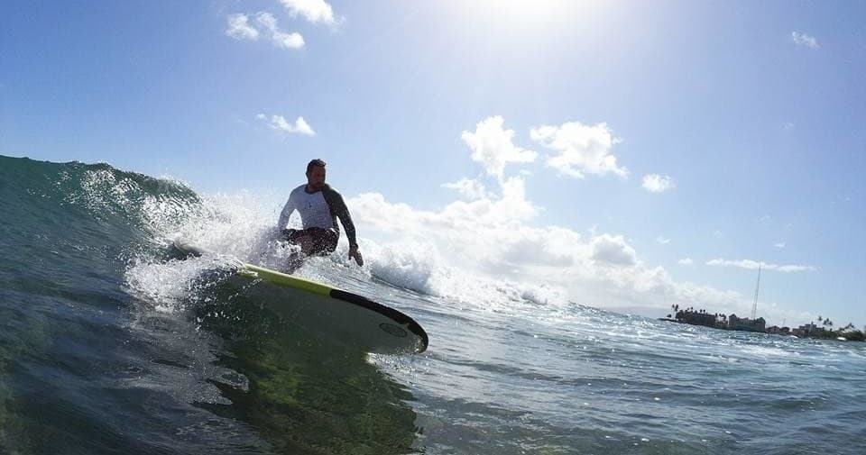 Surfer carving a large wave under bright sun on tropical ocean