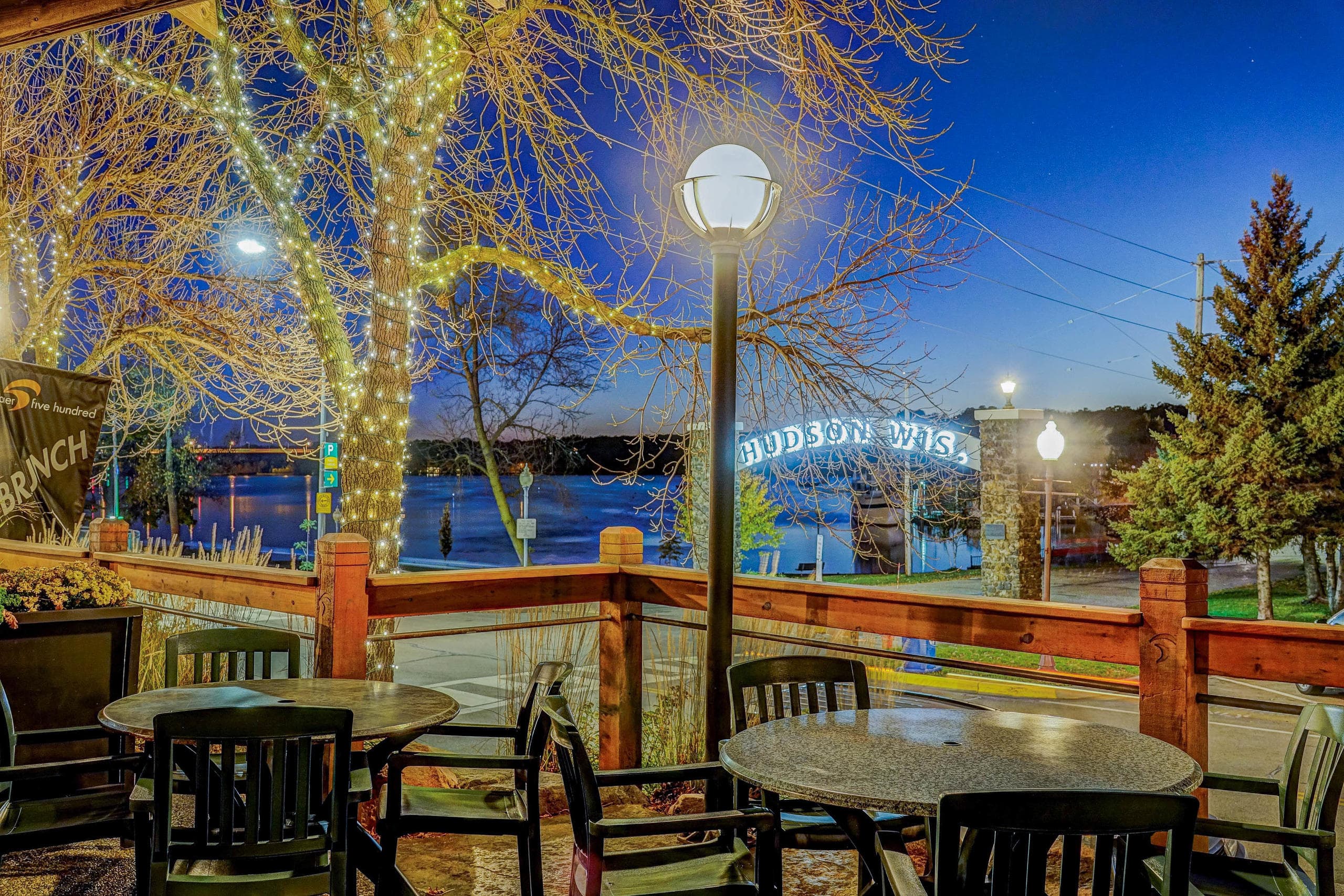 Outdoor waterfront patio dining at dusk with string lights