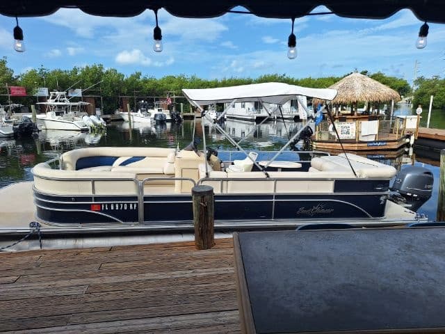Pontoon boat moored at Key West tiki-bar marina, leisure cruise