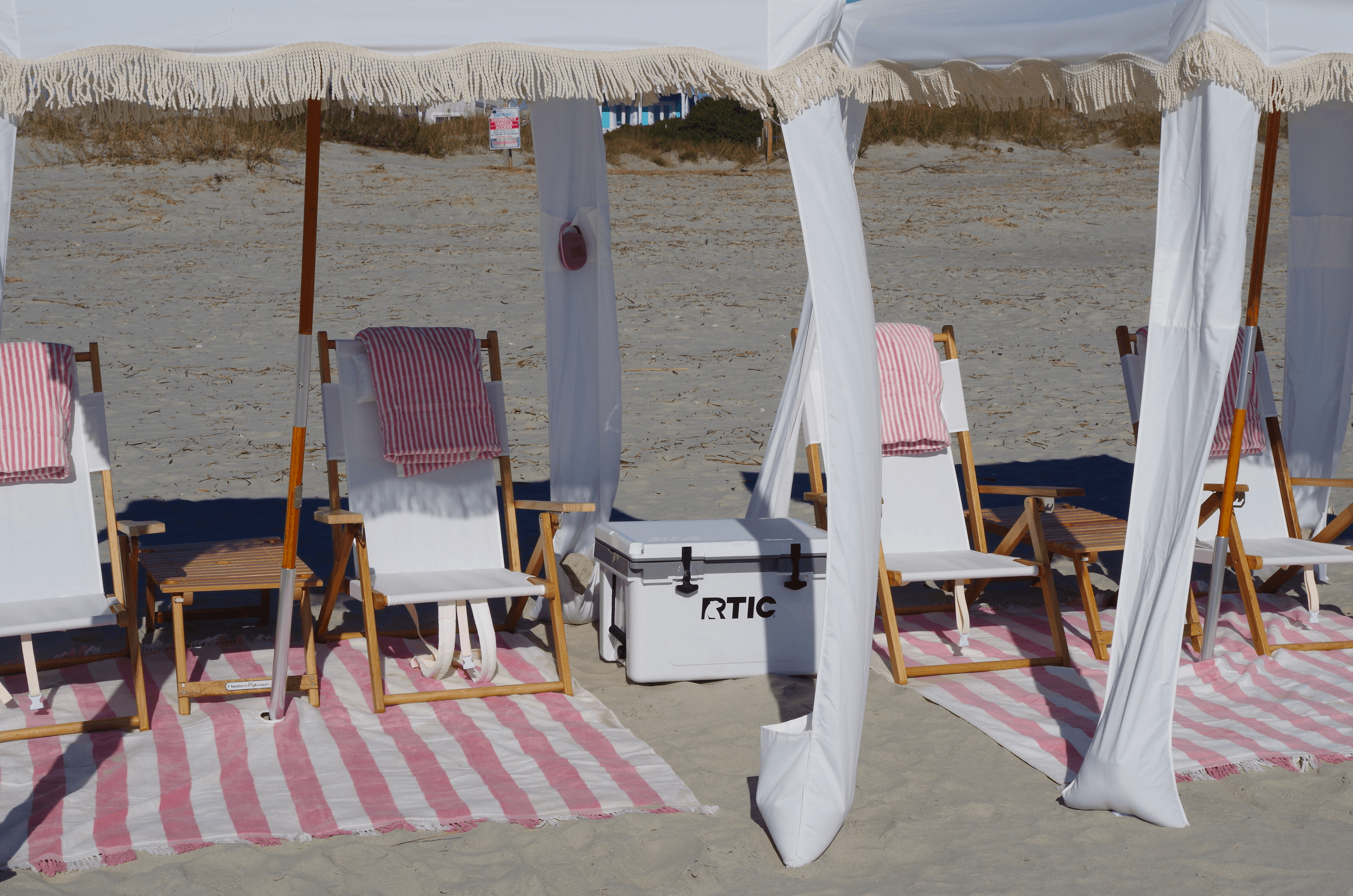 Row of beach chairs and cooler under cabana canopy on beach