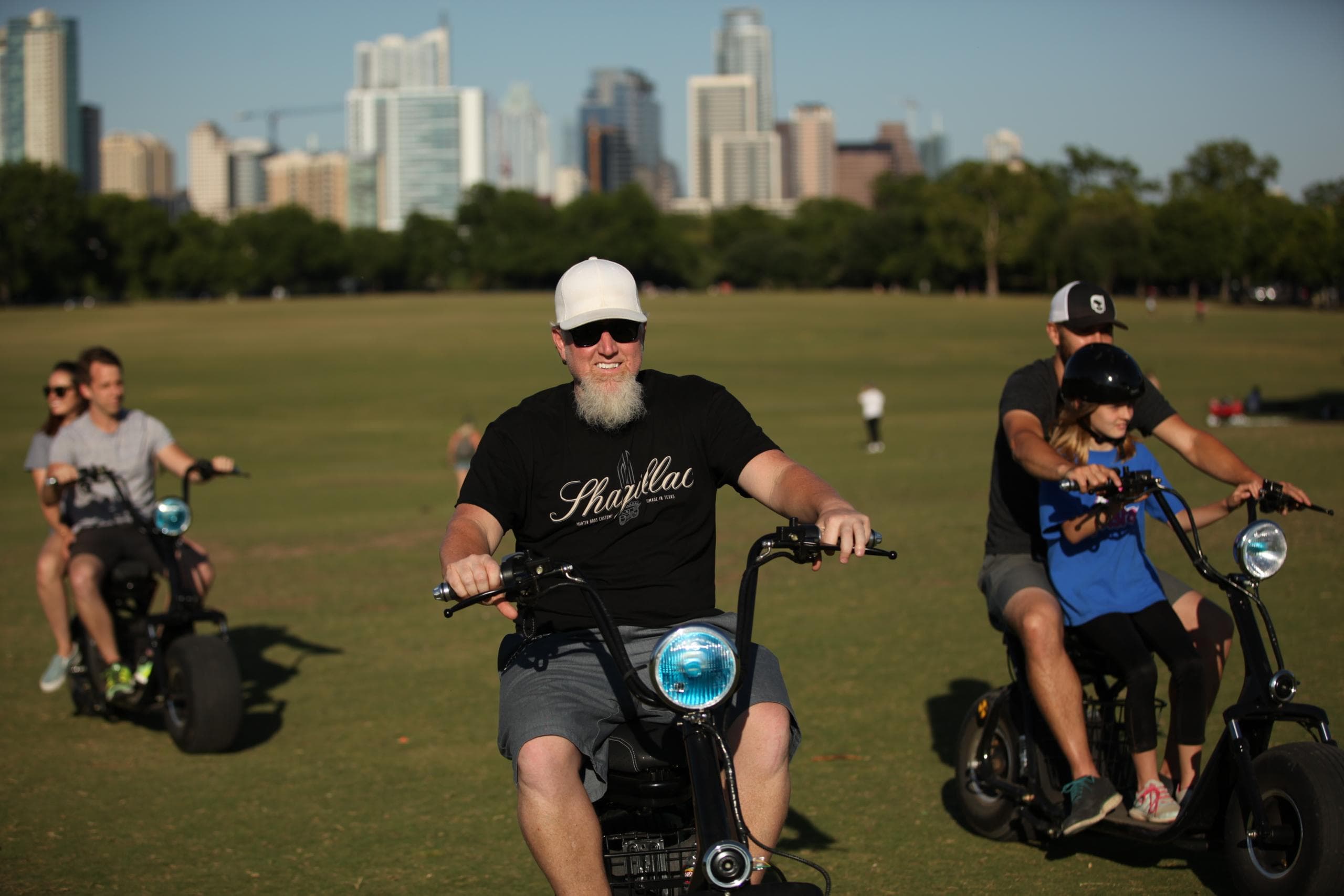 Lead rider on fat-tire scooter with city skyline in background