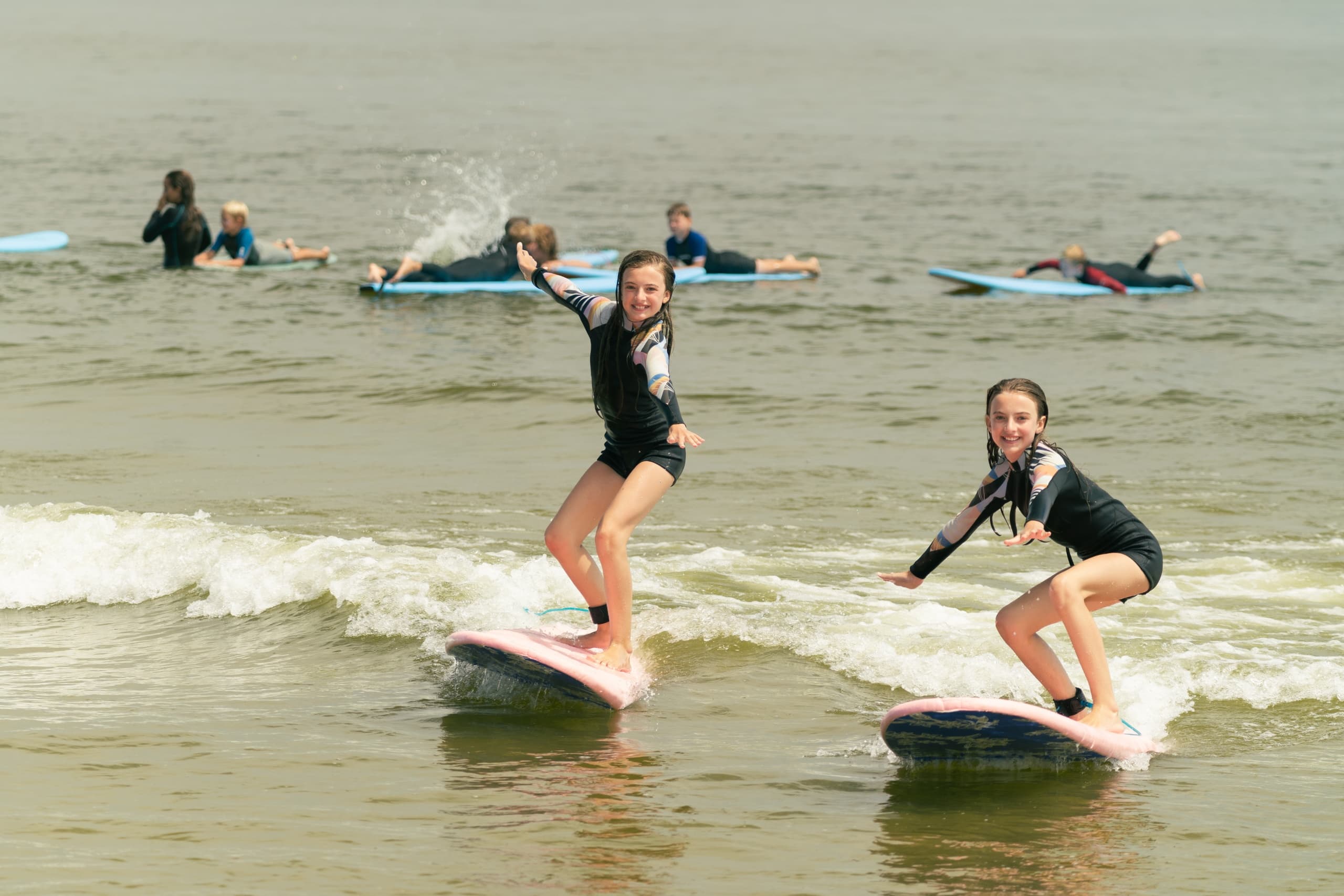 Two young surfers catching small waves in shallow coastal water