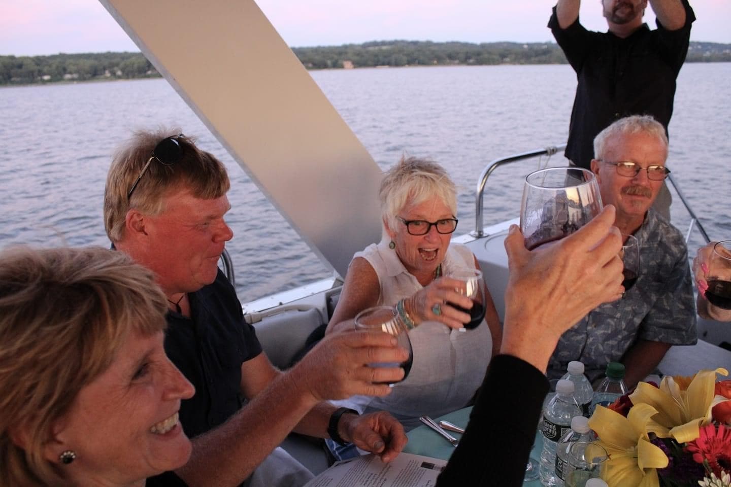 Group toasting aboard small pleasure boat on a lake cruise