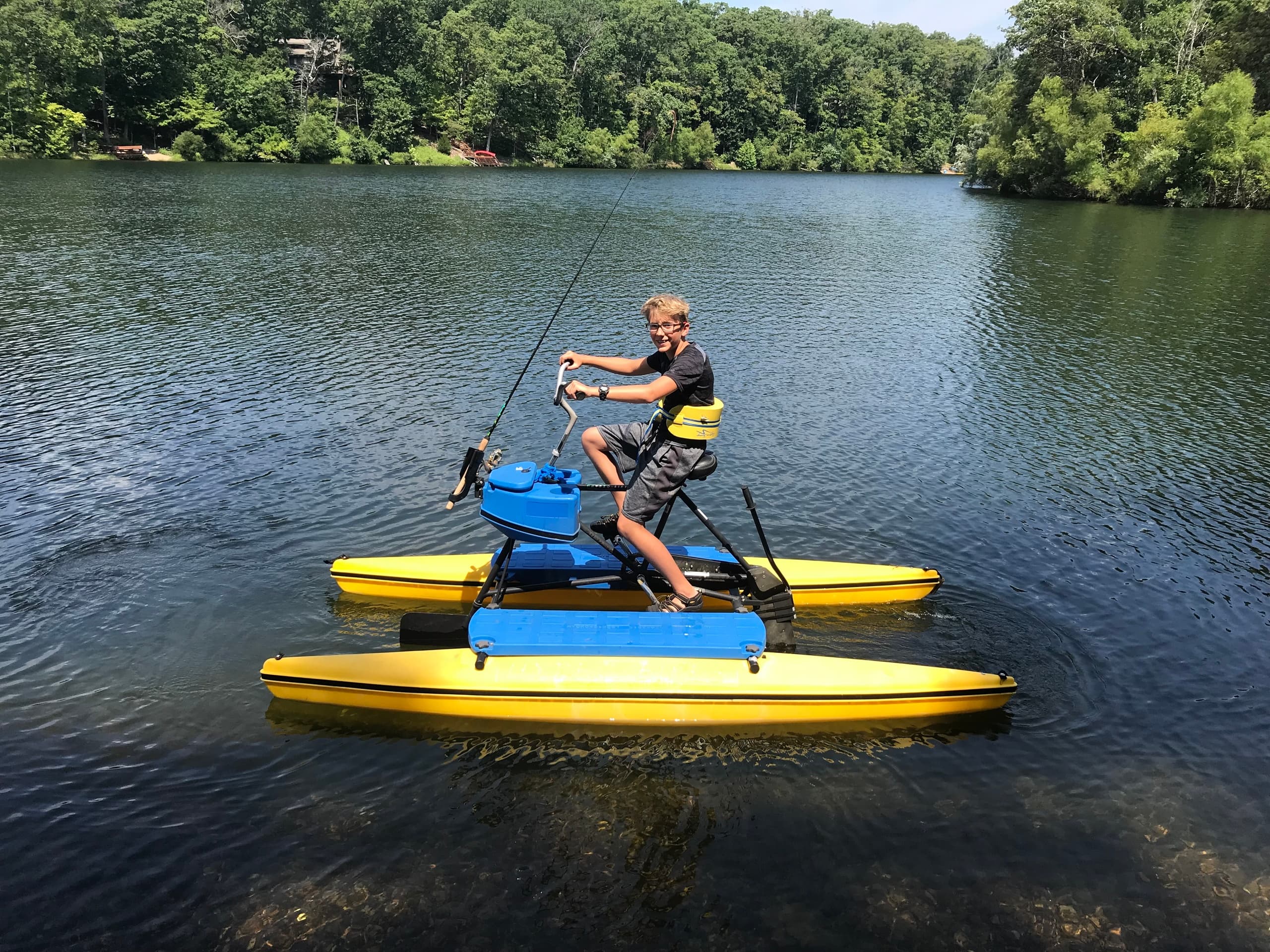 Rider on a yellow water bike pedaling across a tranquil lake