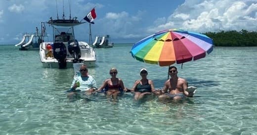 Friends lounging in crystal shallows near anchored charter boat