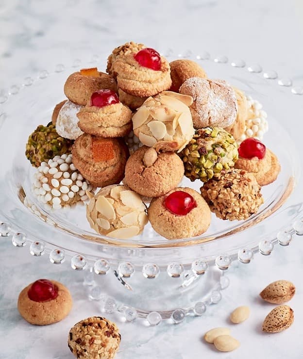 Assorted pastries on glass stand at bakery display, close-up