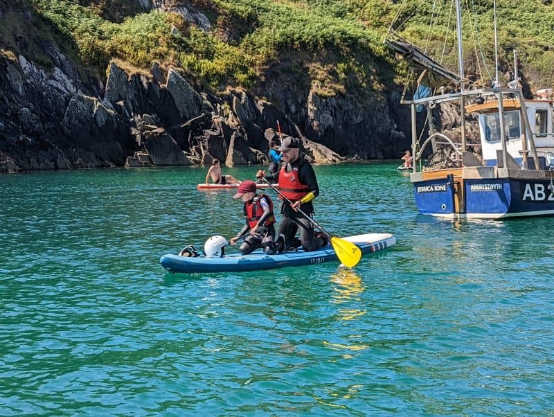 Stand up paddleboarders exploring turquoise bay near fishing boat