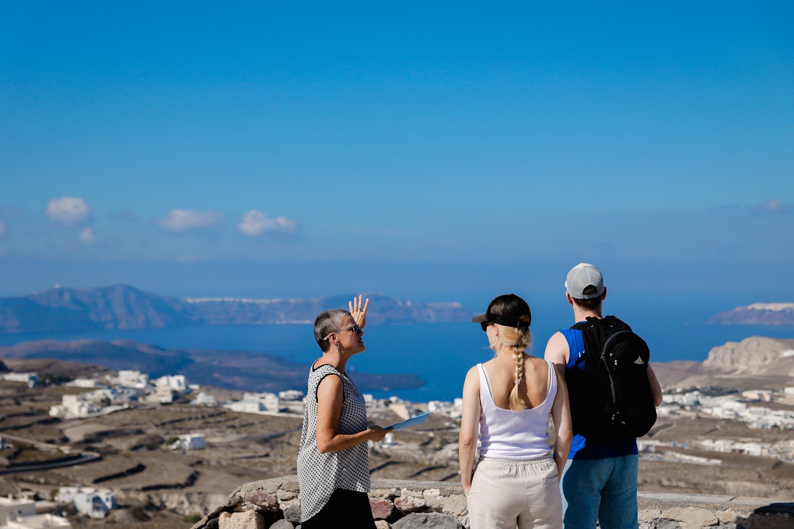 Tourists viewing Santorini caldera panorama from cliff edge