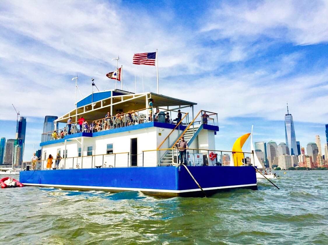 Blue party ferry cruising NYC waterfront with passengers