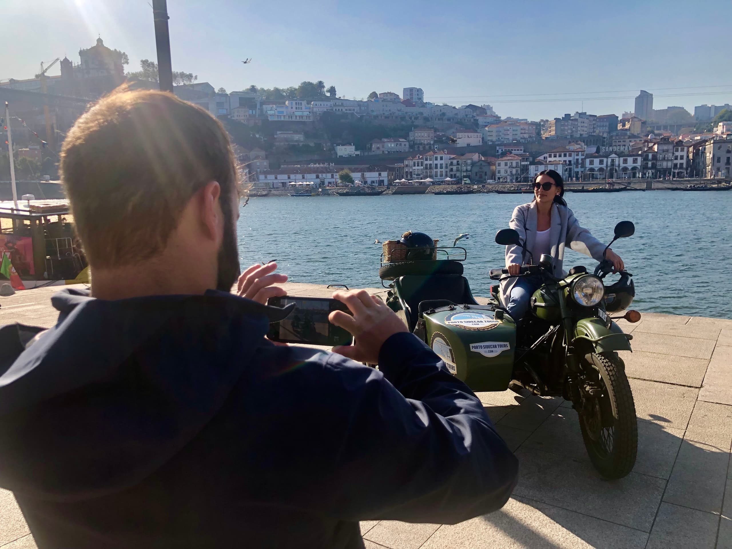 Rider and photographer at waterfront posing with sidecar bike