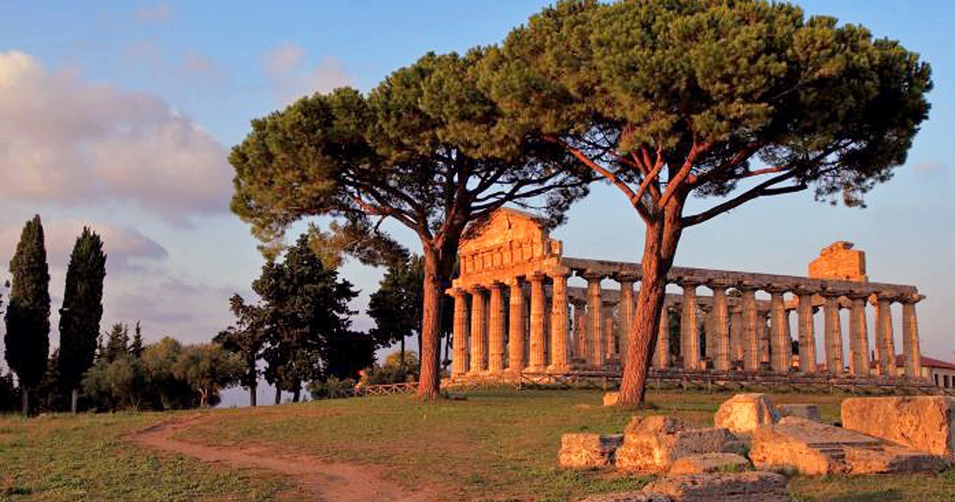 Ancient Paestum temple framed by Mediterranean pines at dusk