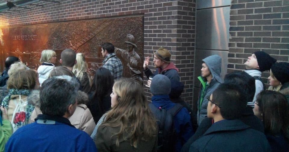Crowd viewing outdoor bronze memorial during NYC walking tour