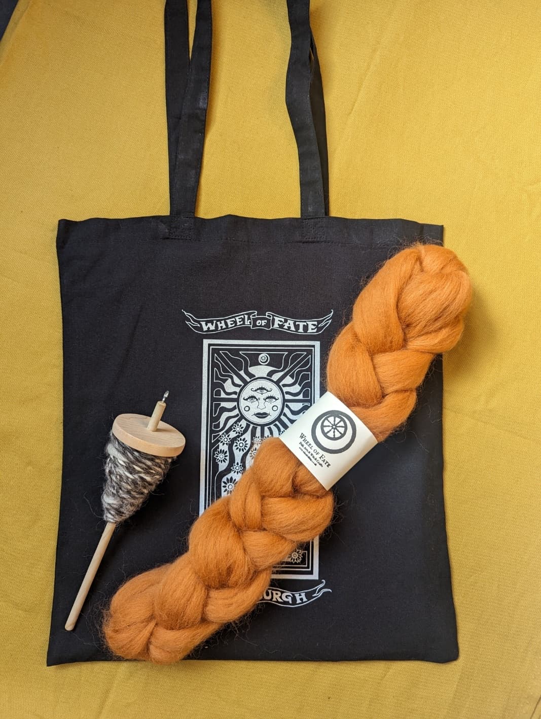 Tote bag with handspun yarn and drop spindle on fabric flatlay