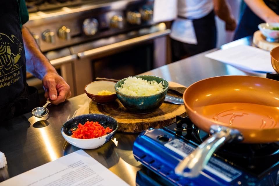 Close-up of cooking station with pans and fresh ingredients for class prep