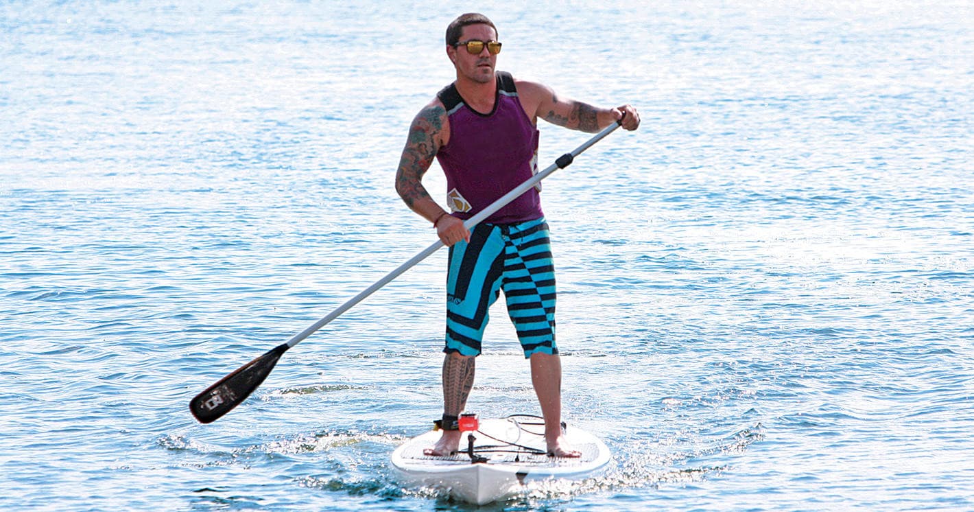 Stand-up paddleboarder cruising on open ocean with bright sunlight