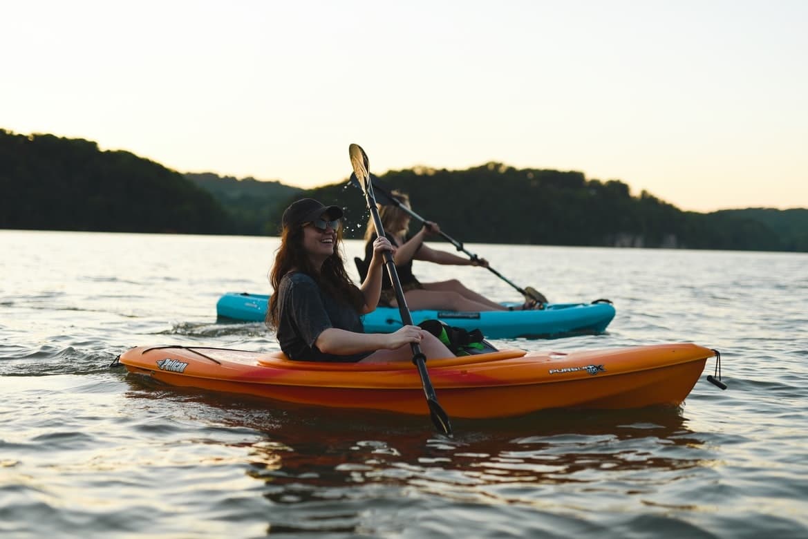 Two kayakers paddling at sunset on tranquil lake