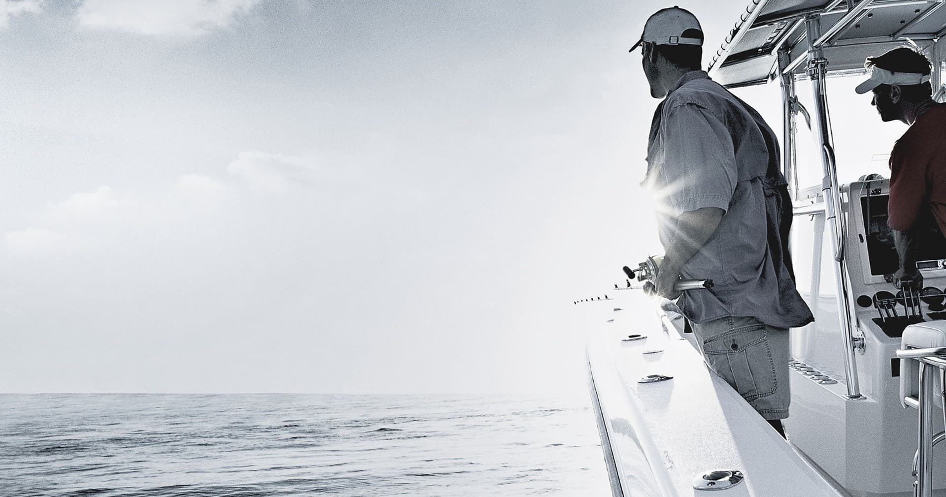 Anglers fishing from a sportfishing boat on open ocean at dawn