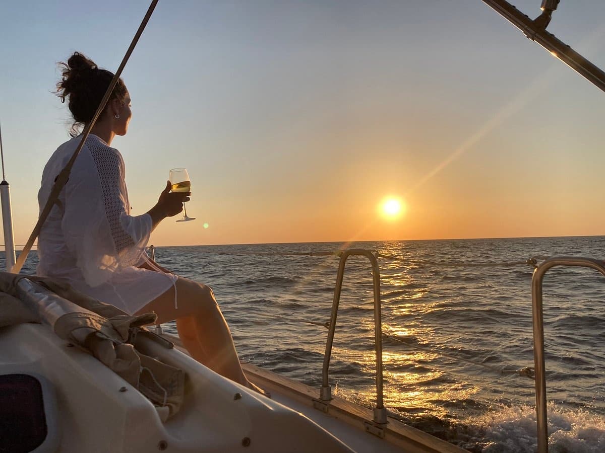 Woman relaxing with wine on sunset sail near Santorini shores