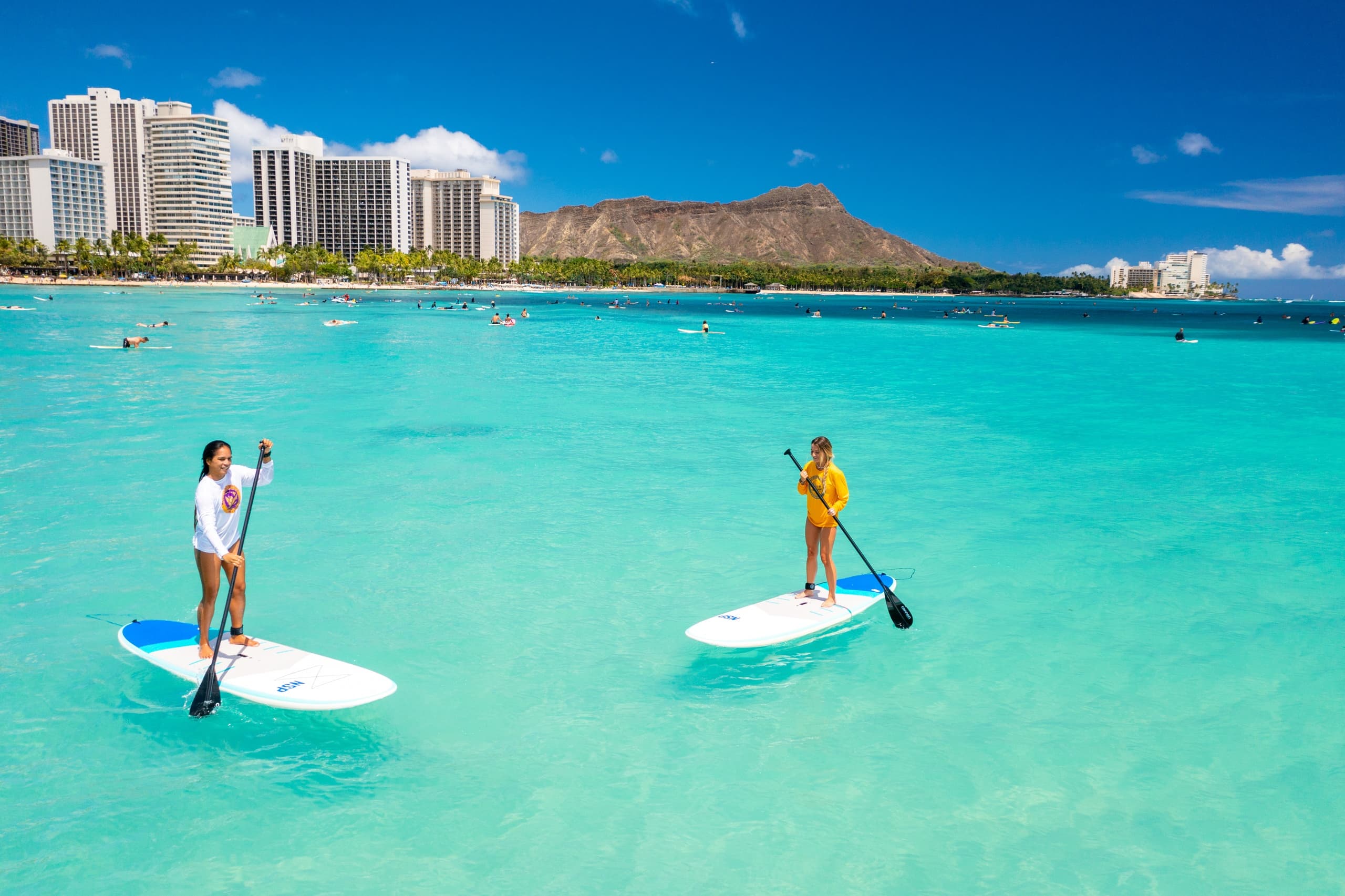 Two standup paddleboarders gliding near Diamond Head in Oahu waters