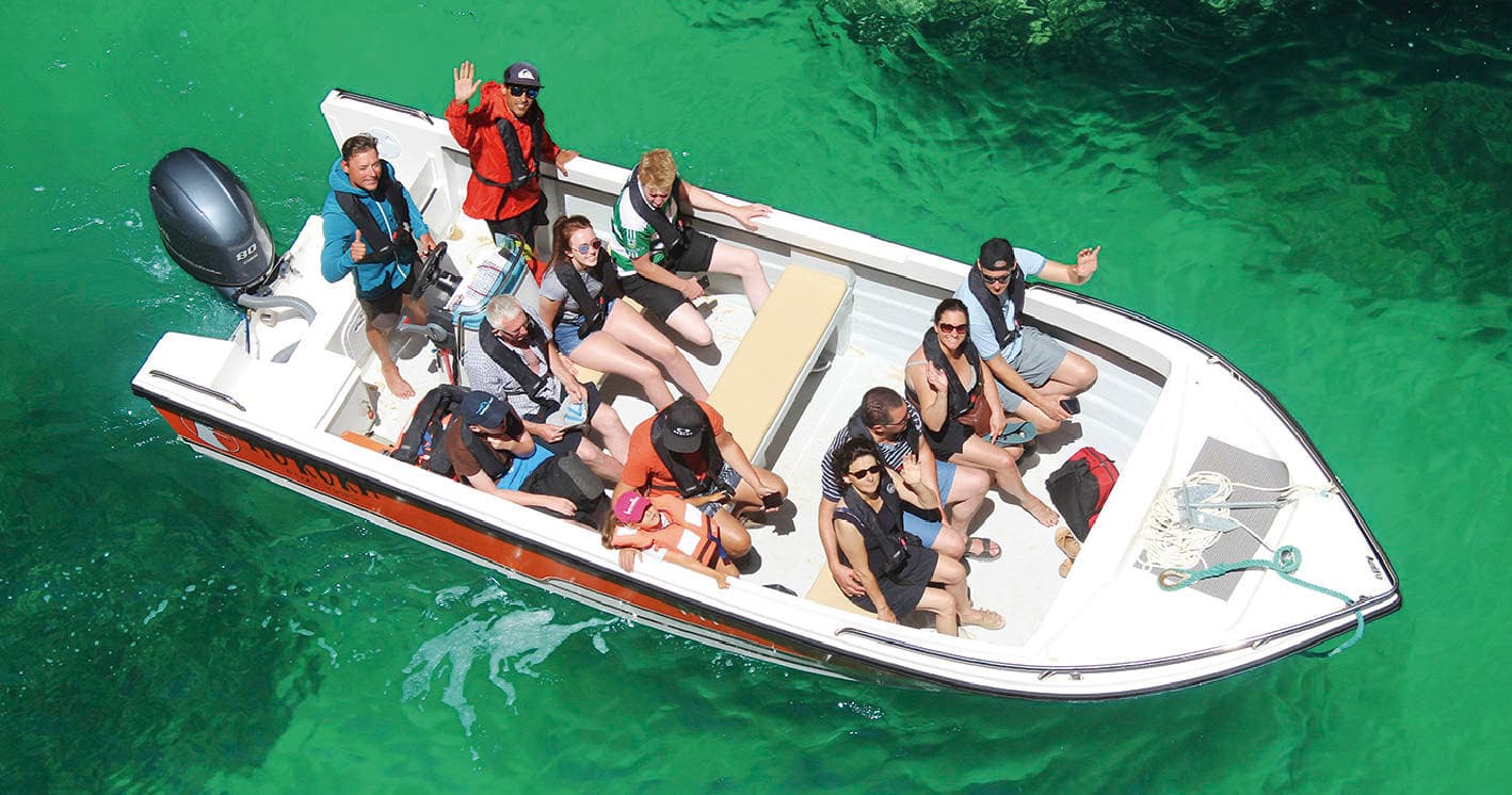 Aerial view of crowded speedboat tour on clear green coastal waters