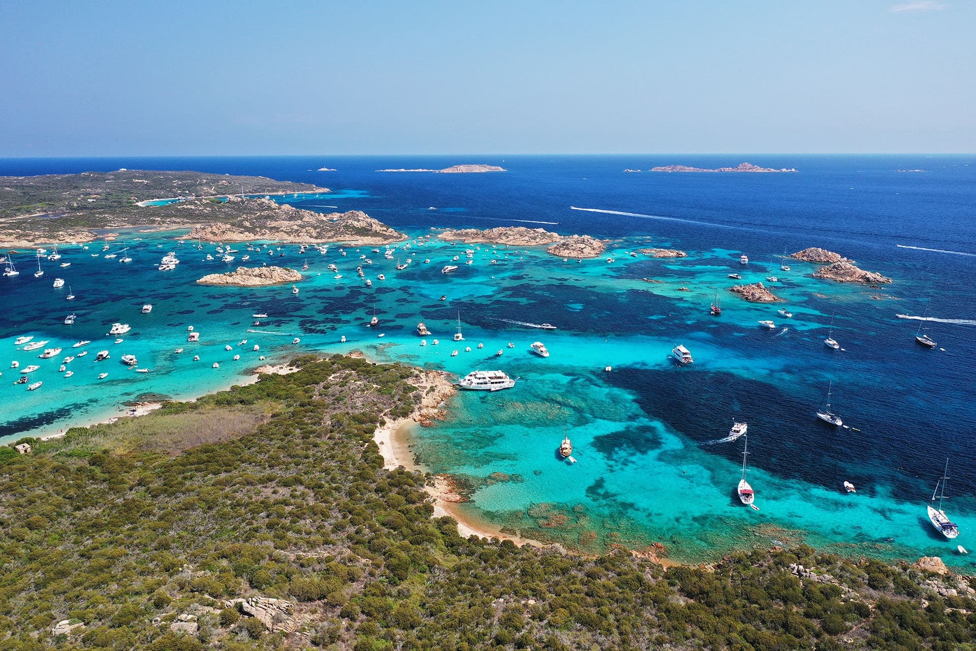 Aerial panorama of crystal bays and multiple anchored boats
