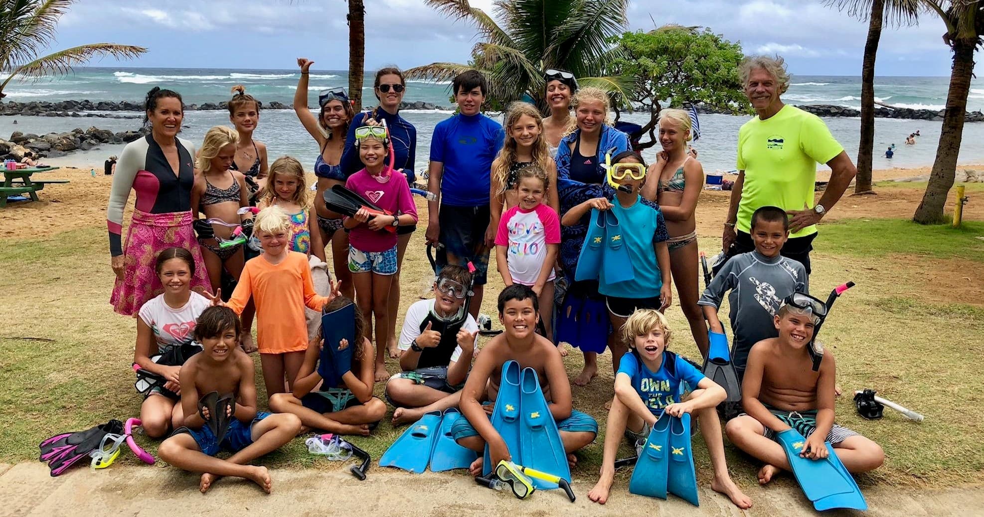 Snorkeling group on tropical beach with reef and palm trees