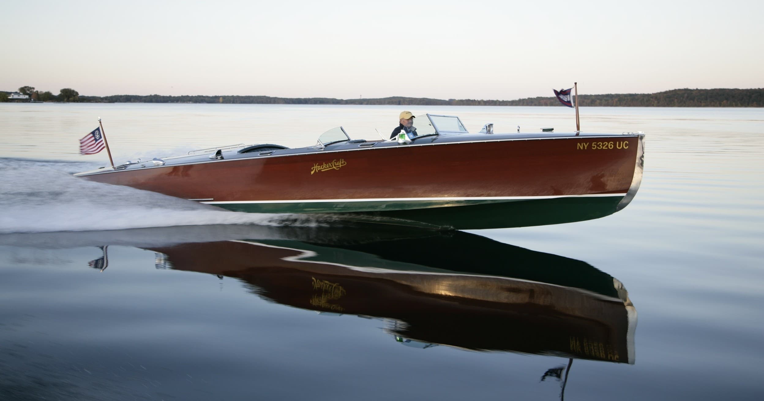 Classic wooden speedboat reflected on calm lake at dusk