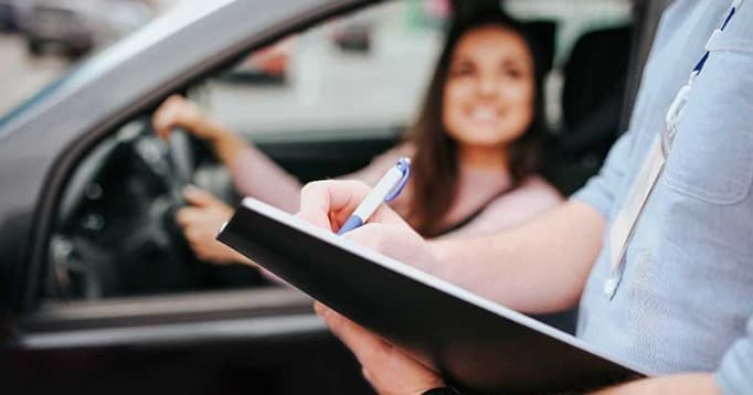Driving instructor with clipboard during behind-the-wheel lesson