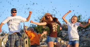 Family jumping on rocky bluff during sunny outdoor adventure