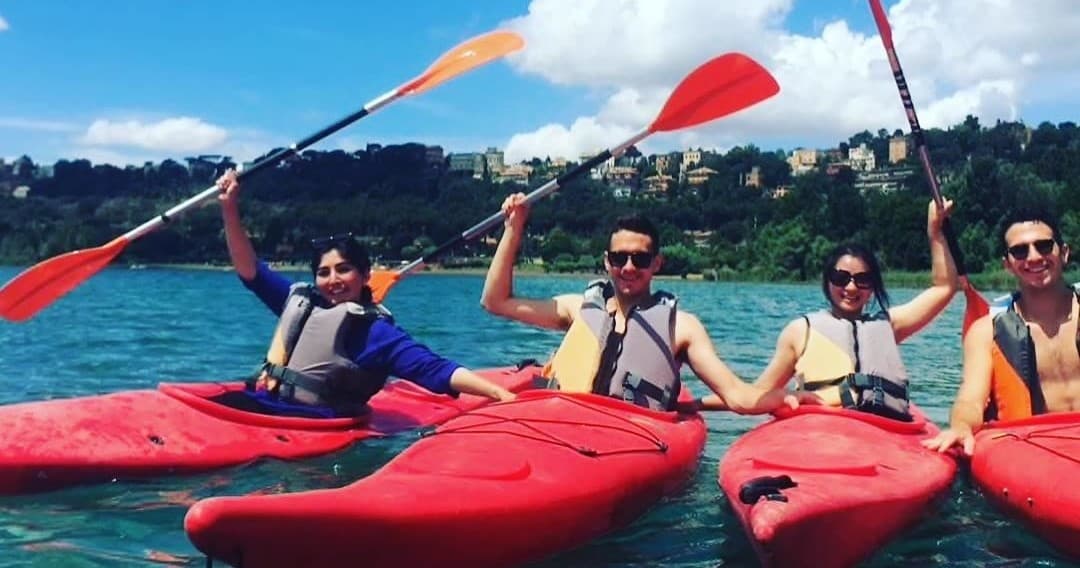 Group kayaking team raising paddles on scenic coastal lake tour