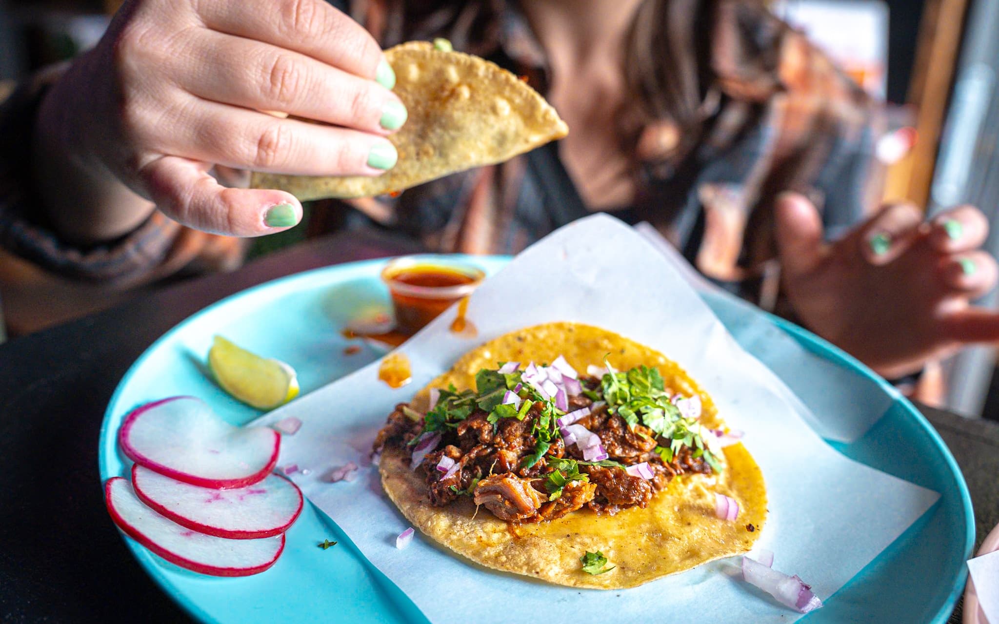 Street-style taco being eaten at casual indoor taqueria