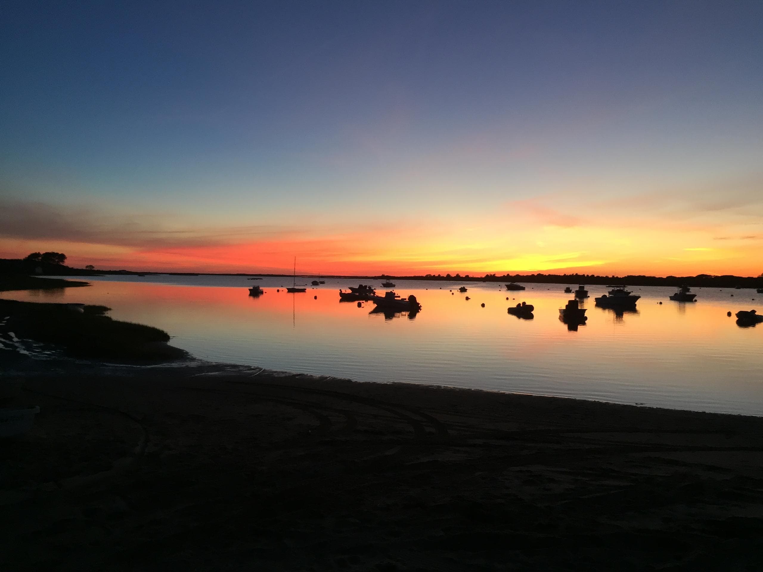 Nantucket harbor sunset with reflective water and moored boats