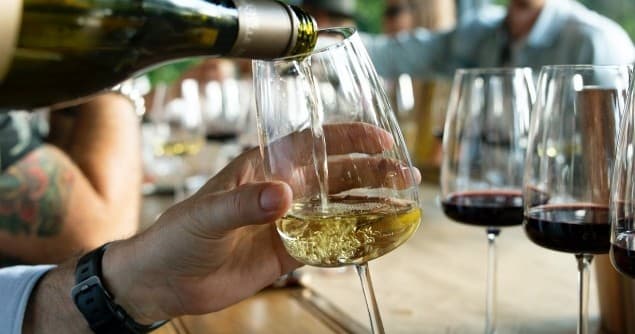 Wine tasting pour into glass at communal table during tasting