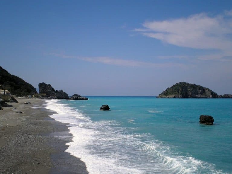 Wide sandy beach with waves and rocky headlands coastal view