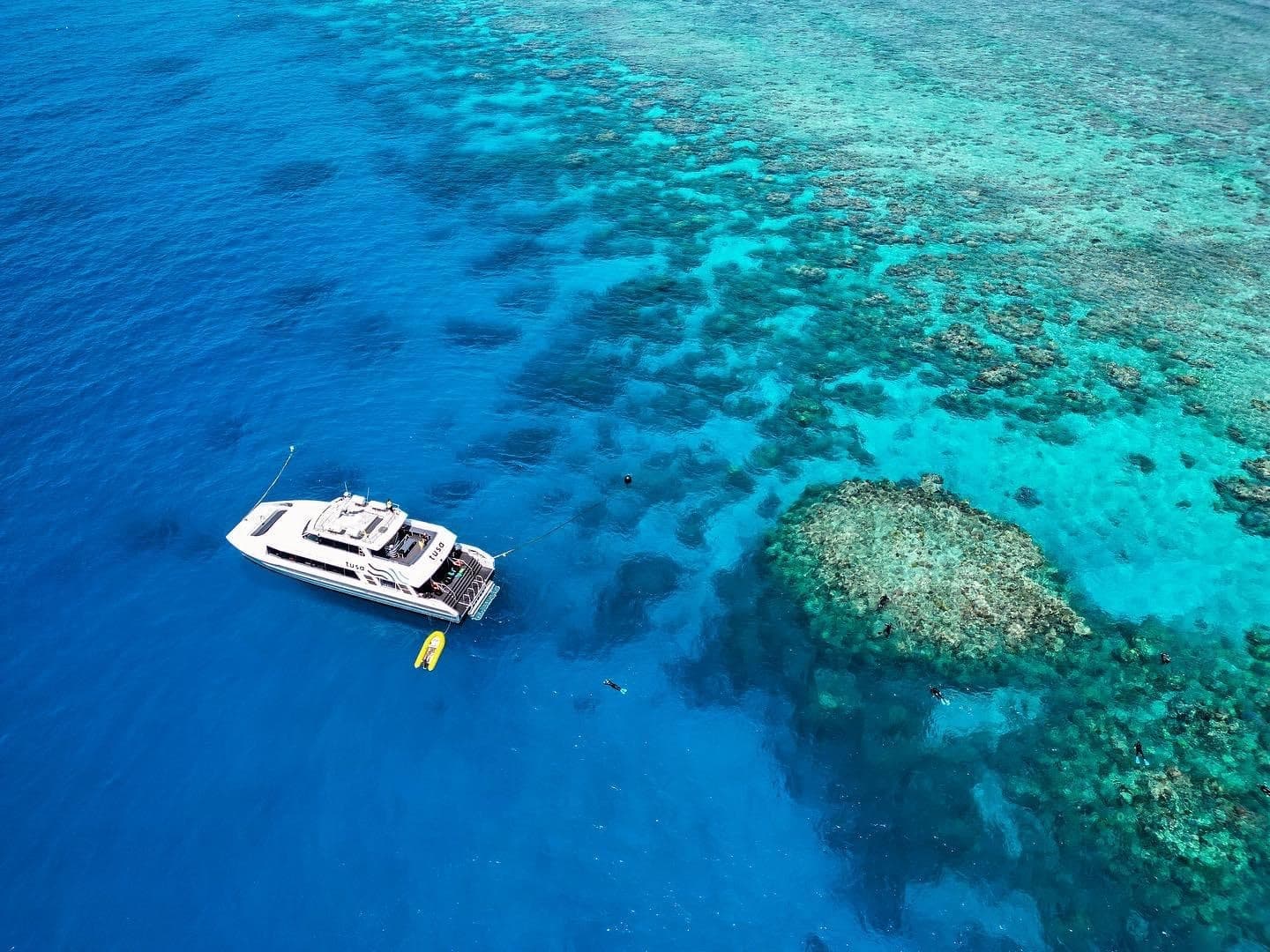 Aerial view of boat anchored near turquoise reef, ocean exploration